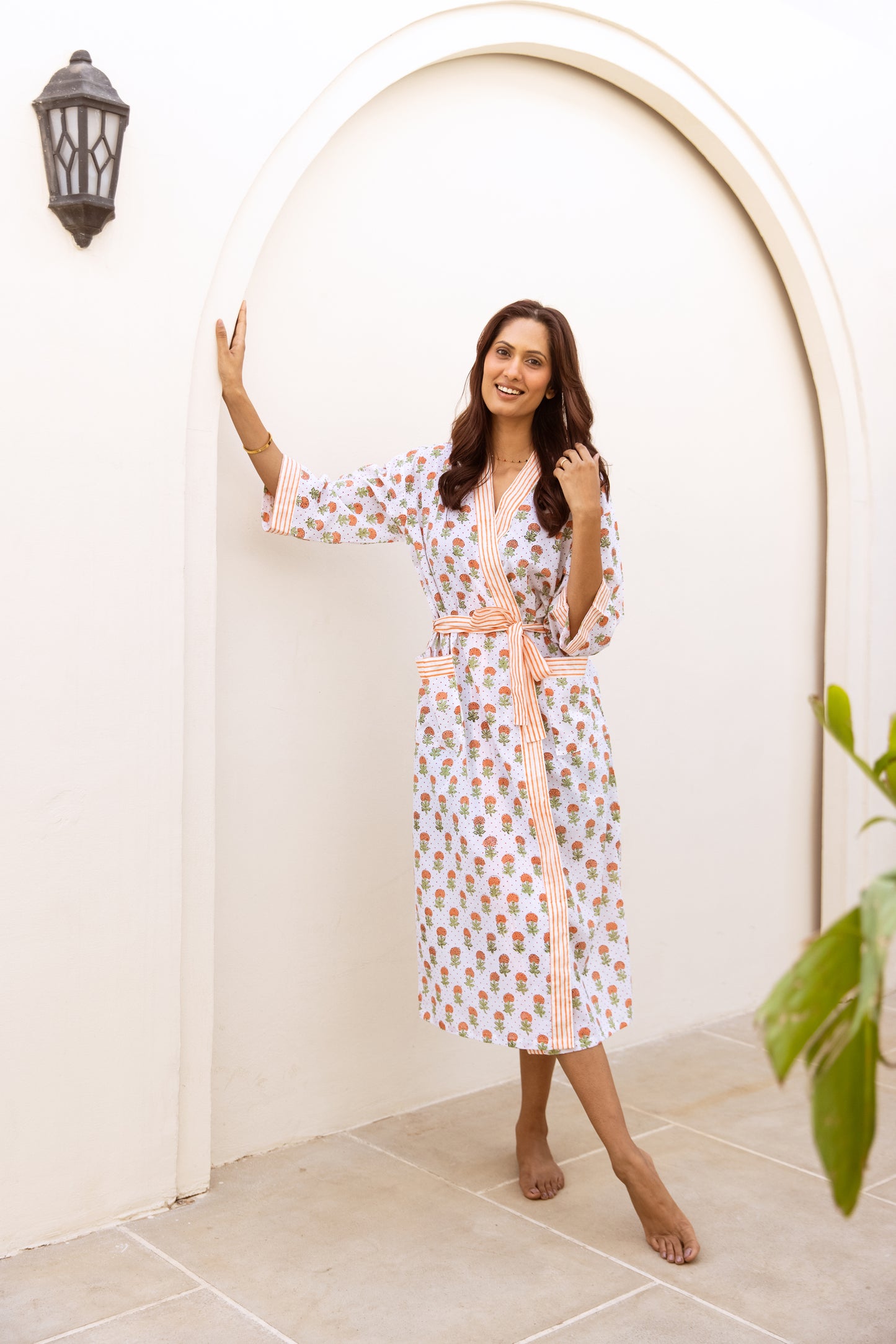Woman in white floral cotton dressing gown standing by arched doorway